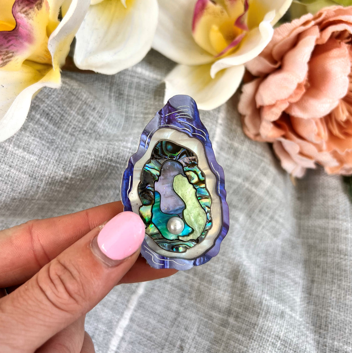 Hand holding an oyster brooch